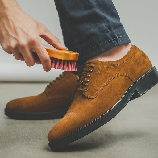 A shoe brush cleaning a suede shoe